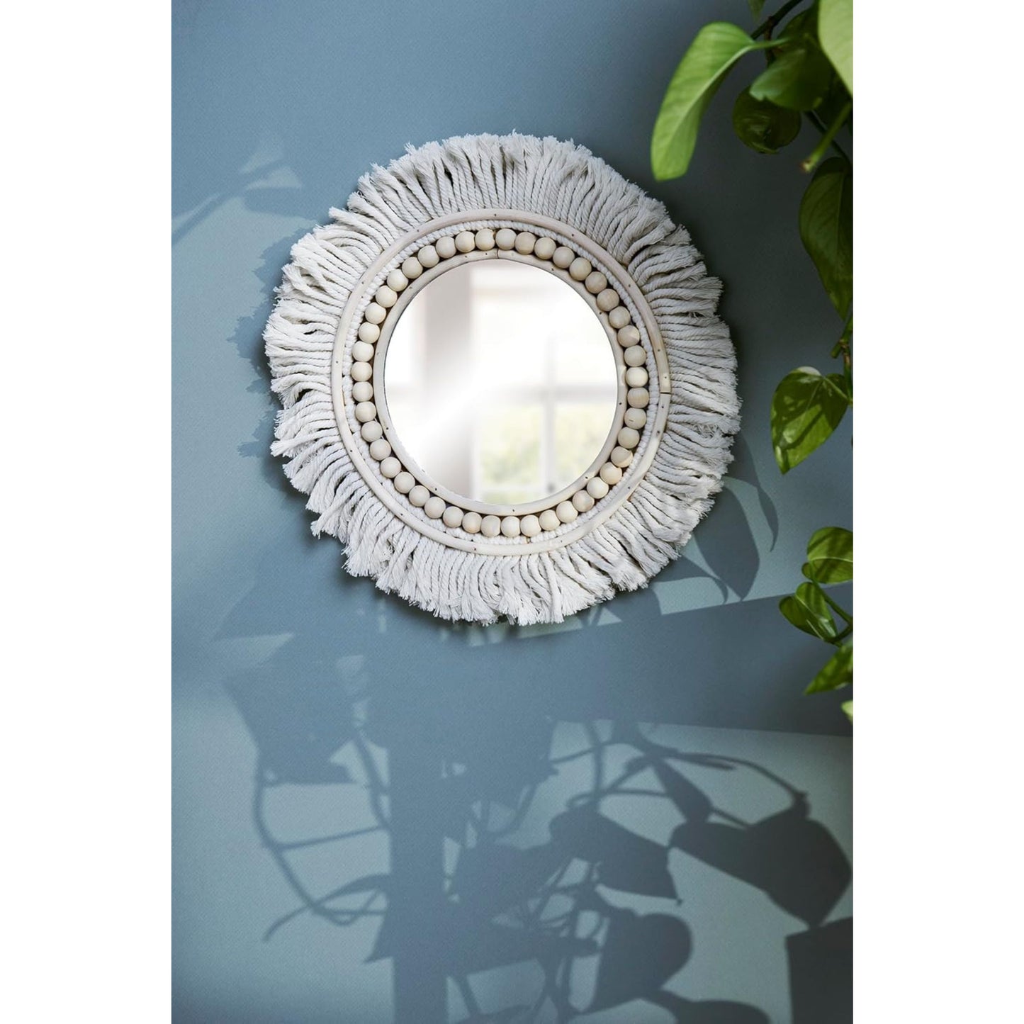 Round mirror with decorative white frame on a blue wall