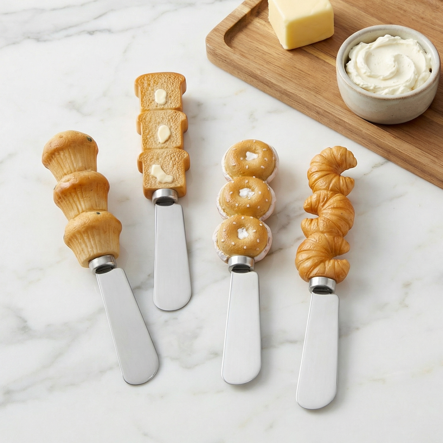 Set of four bread-shaped cheese knives on a marble surface with a wooden board and food items.