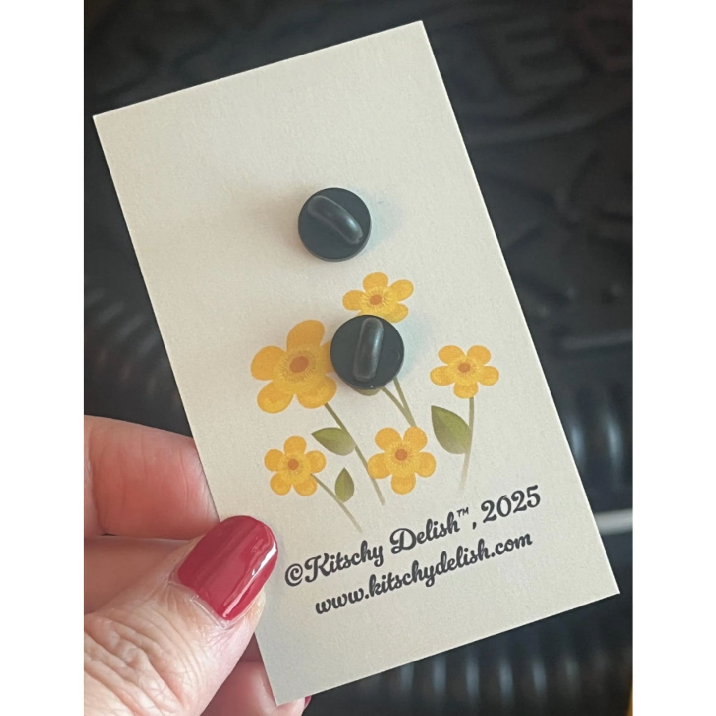 Back part of an enamel pin on a card with yellow flowers design