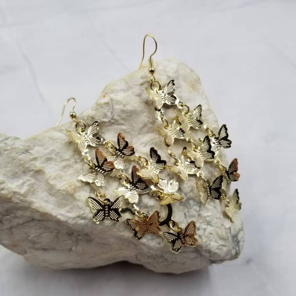 Butterfly-shaped earrings on a textured stone surface