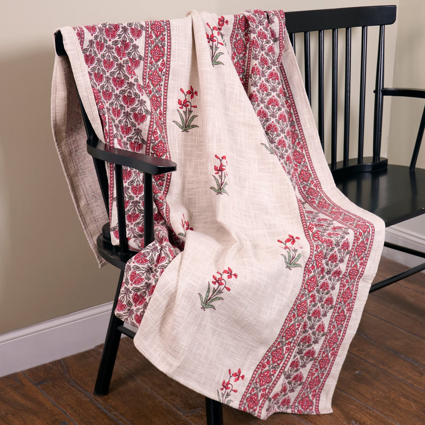 Decorative throw blanket with floral patterns draped over a black chair.