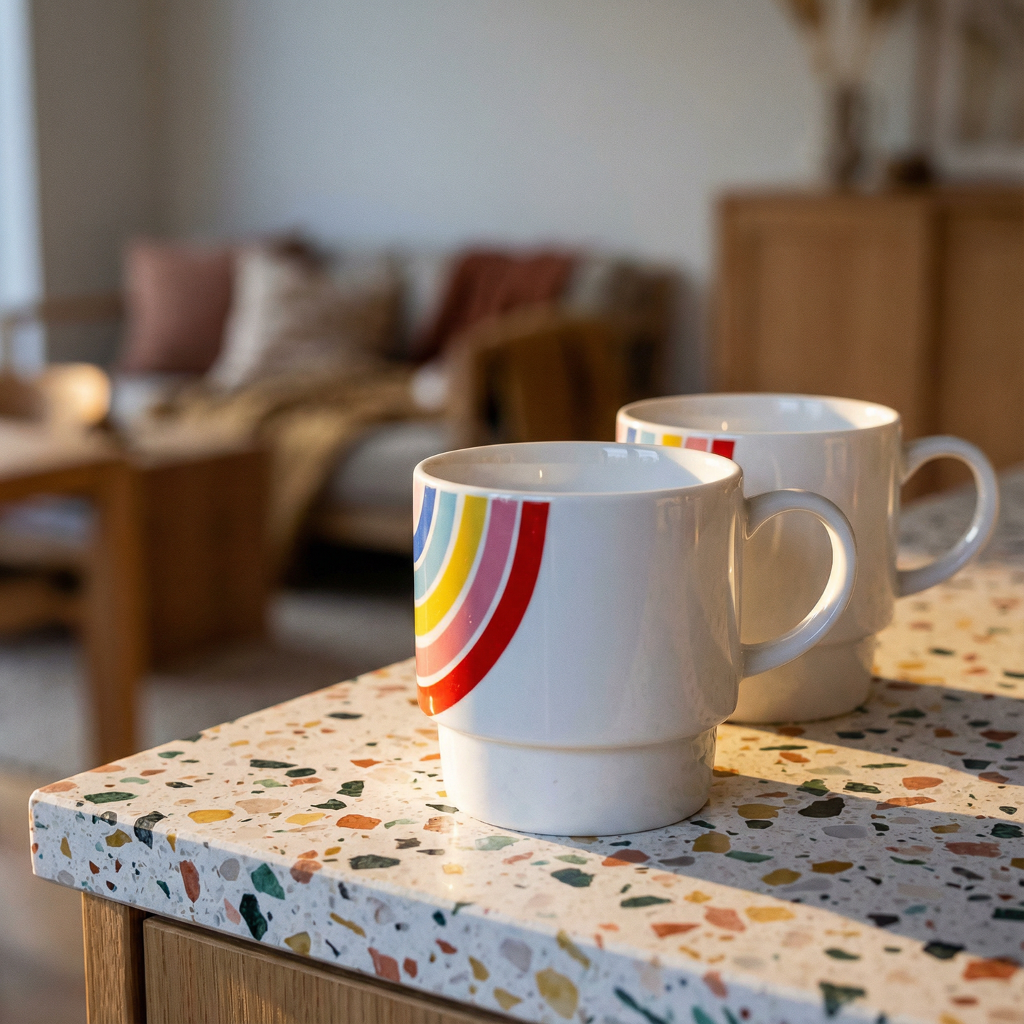 Two mugs on a terrazzo countertop with a blurred indoor setting