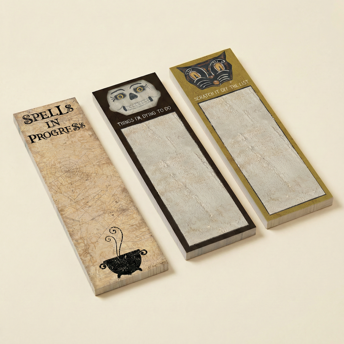 Three decorative notepads with unique spooky designs on a beige background