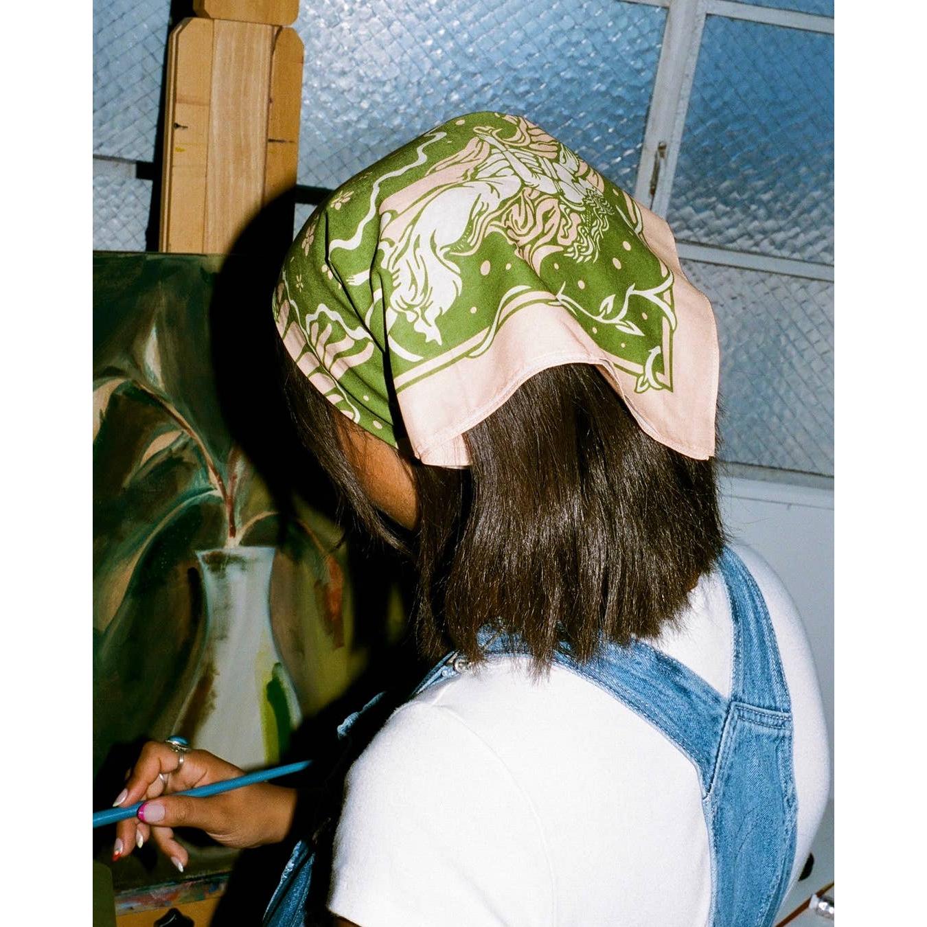 Person wearing a green patterned headscarf in an indoor setting