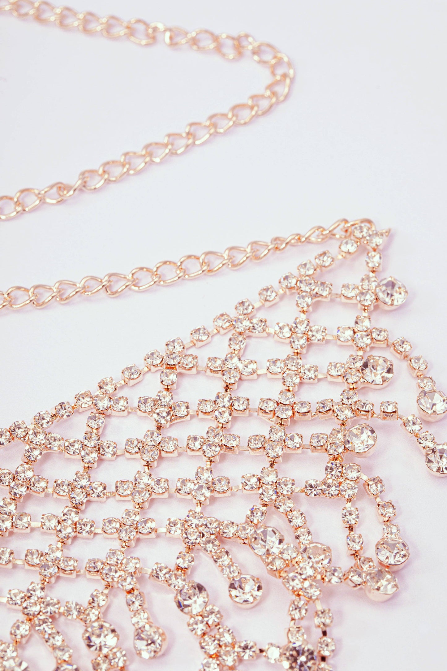 Rose gold chain with crystals on a light pink background