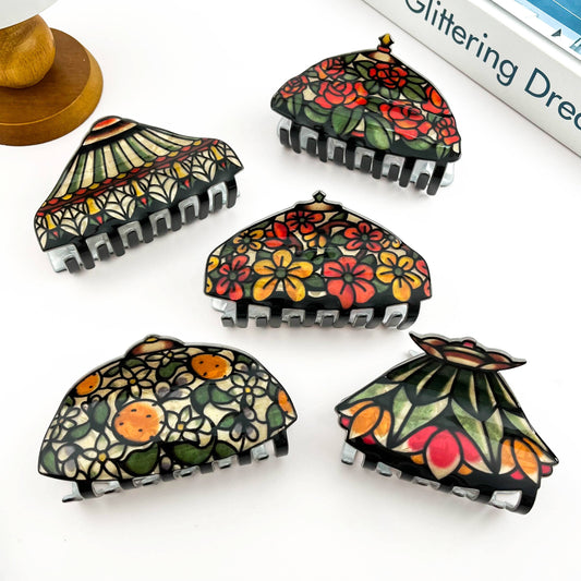 Five decorative claw hair clips, each featuring a different colorful floral and fruit pattern with black claw bases.