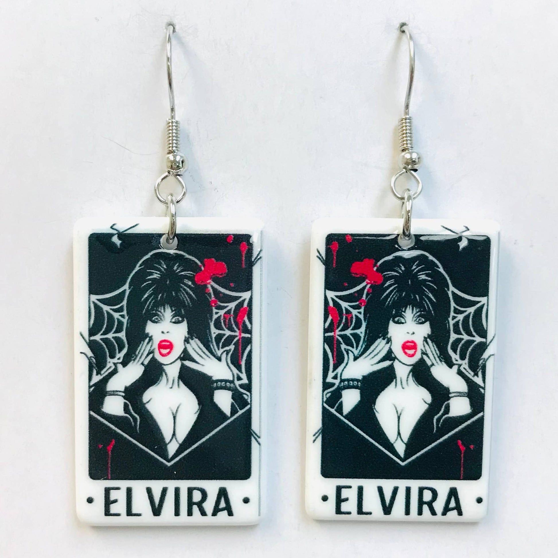 Pair of earrings featuring Elvira character with red lips and black hair 