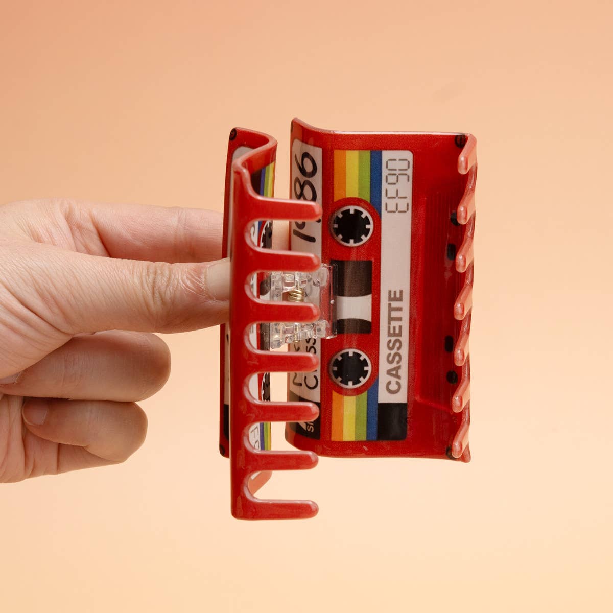 A red plastic claw hair clip designed to look like a vintage cassette tape,