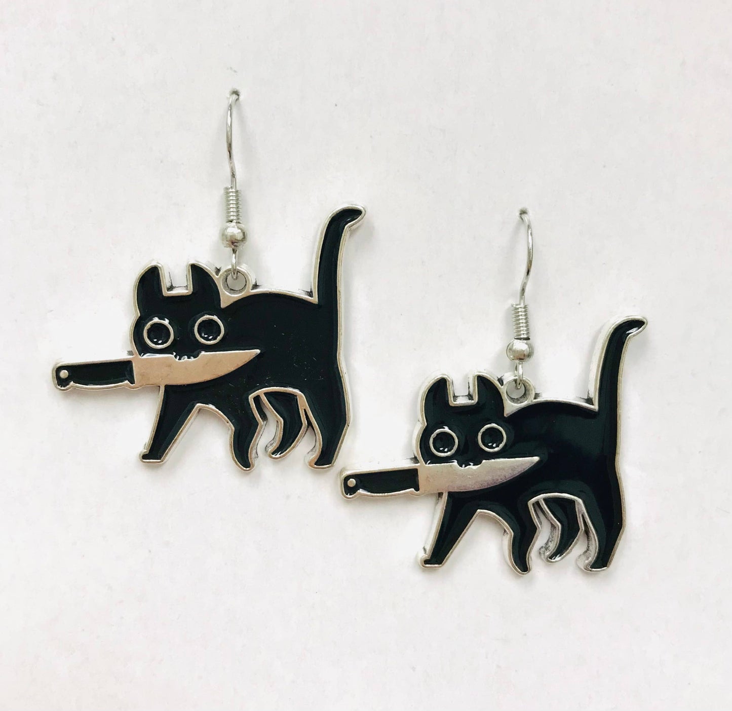 Black cat-shaped earrings holding a knife with its mouth
