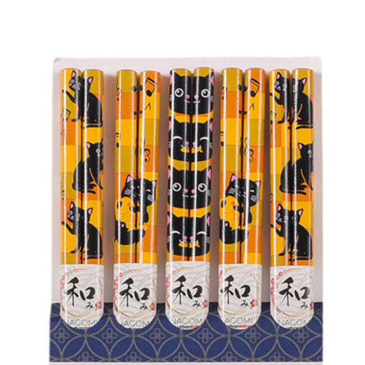 A set of five chopsticks in a holder with a blue patterned base. The chopsticks are yellow and black with a repeating cat illustration pattern, and have white paper bands at the bottom with Japanese characters.