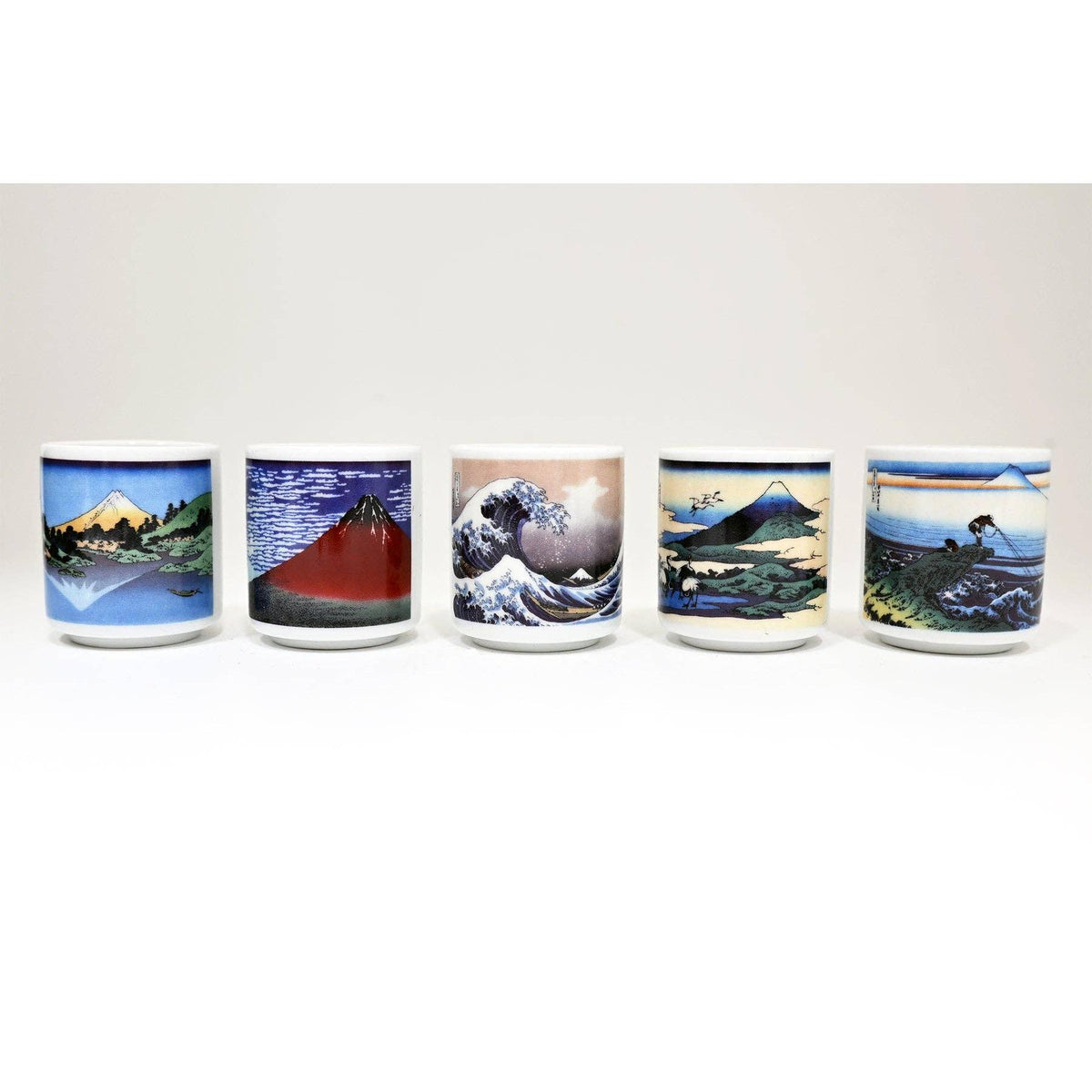 Five ceramic cups with artistic designs of Mount Fuji and a wave 