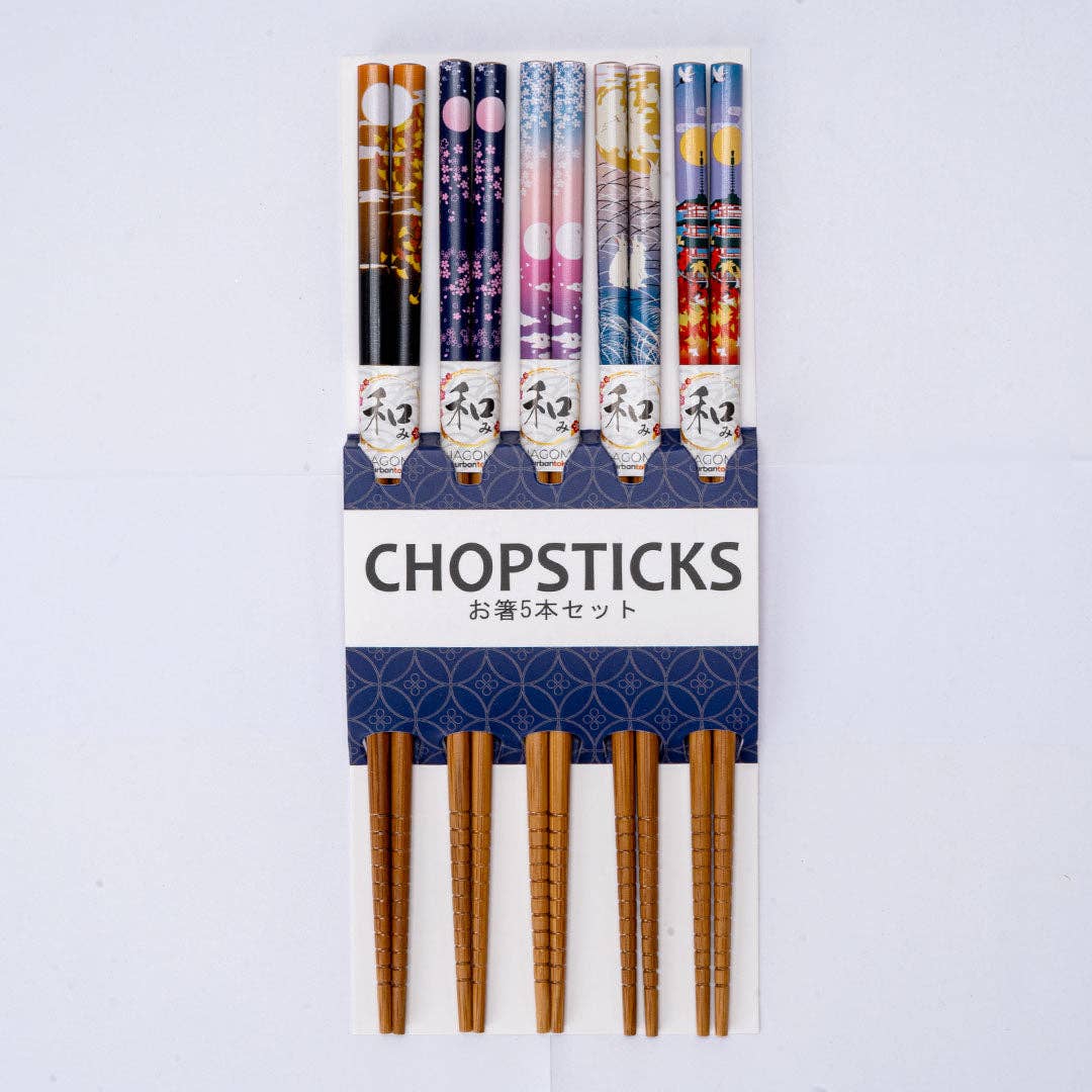 A set of five decorative chopsticks in a white and navy cardboard holder. The chopsticks feature various colorful Japanese patterns on the upper shafts and natural wood-colored tips.