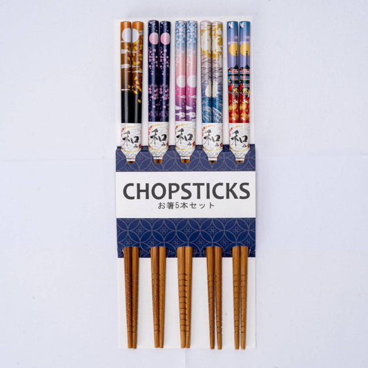 A set of five decorative chopsticks in a white and navy cardboard holder. The chopsticks feature various colorful Japanese patterns on the upper shafts and natural wood-colored tips.