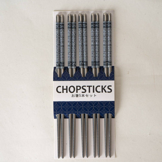 A set of five decorative stainless steel chopsticks in a white and navy blue cardboard package