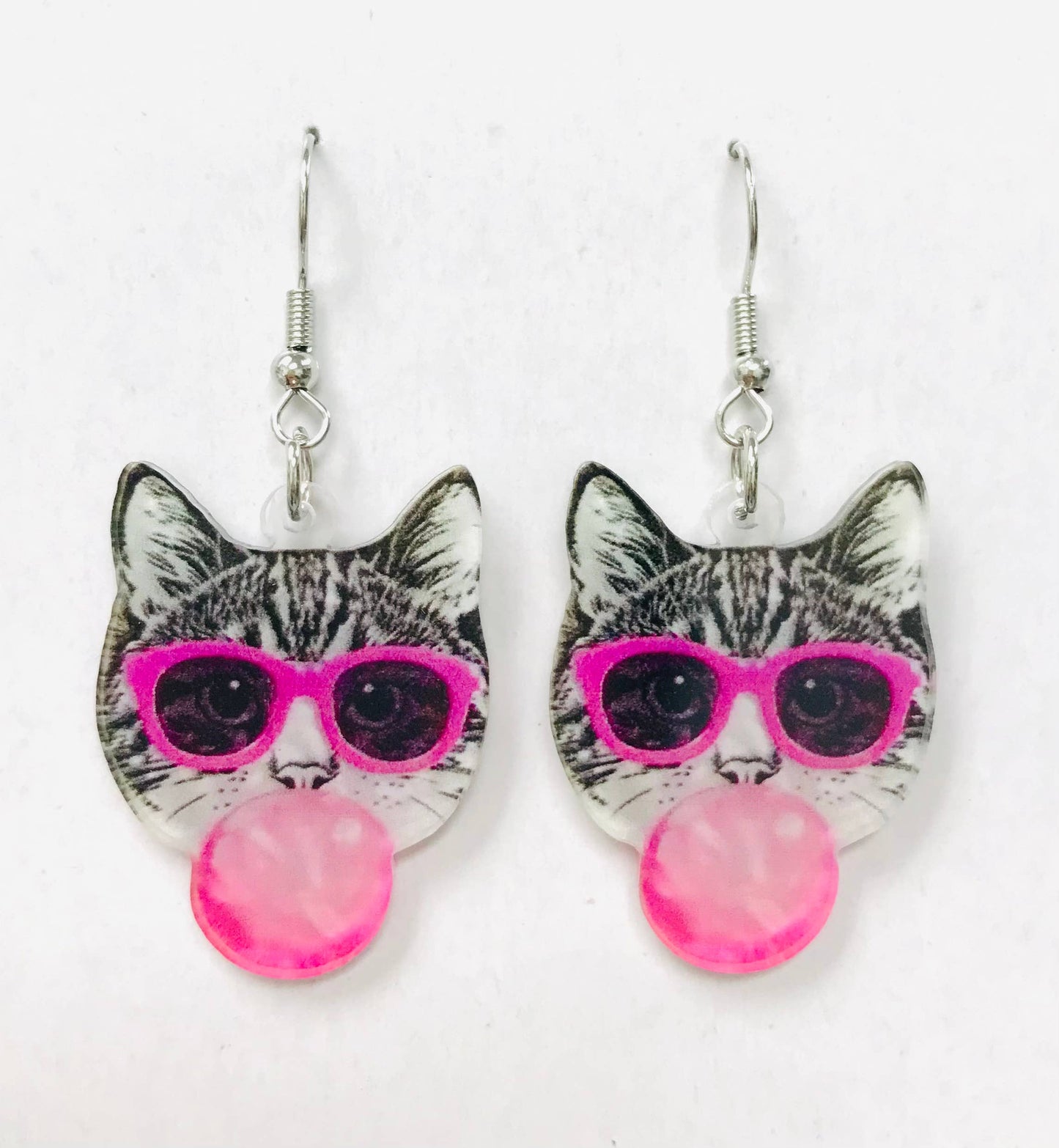 Cat-shaped earrings with pink sunglasses and pink beads on a white background