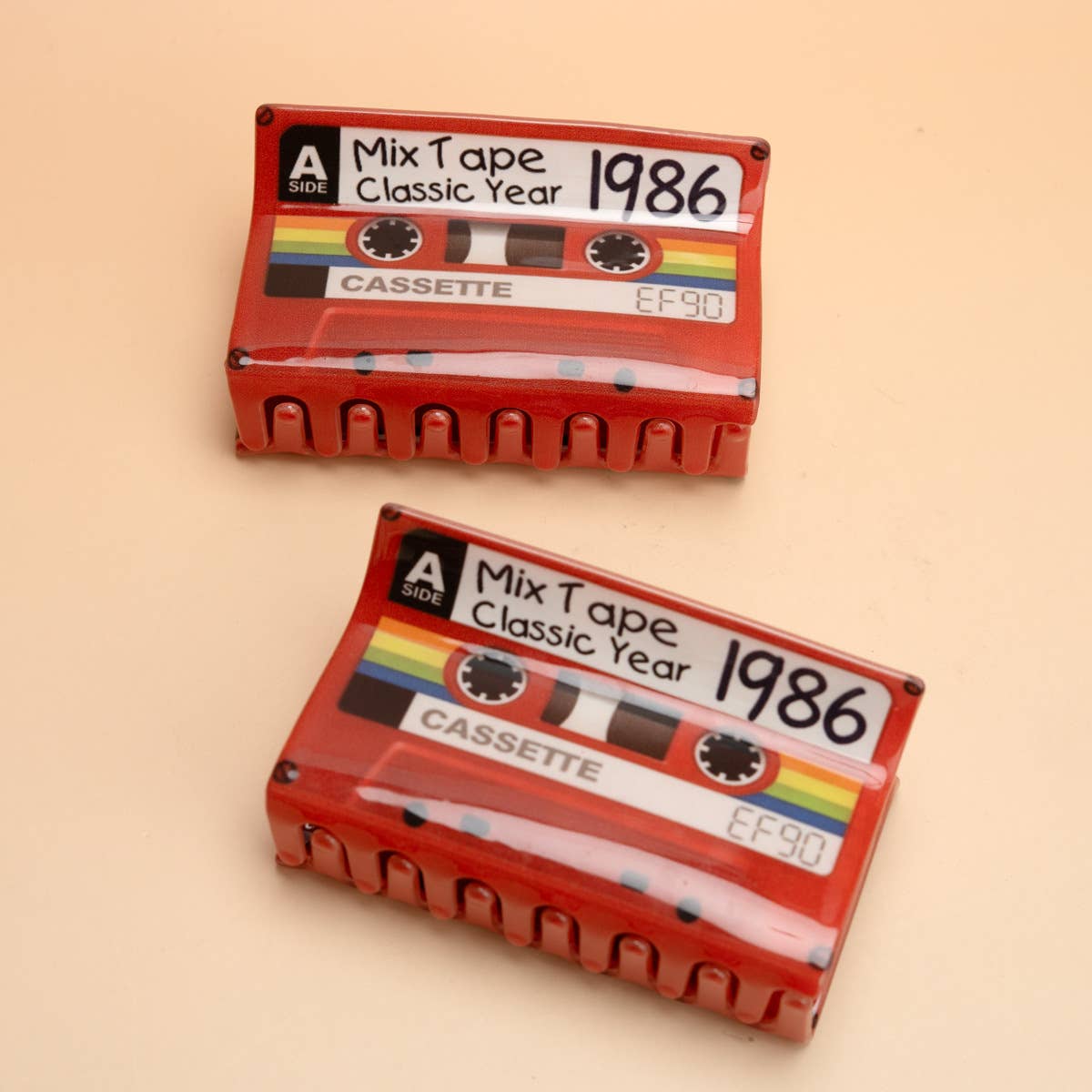 Two red cassette tape-shaped hair claws with printed labels reading 'Mix Tape Classic Year 1986 CASSETTE' and 'EF90'
