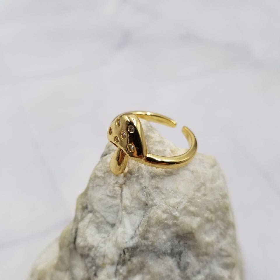 Mushroom gold ring with small stones on a textured stone surface