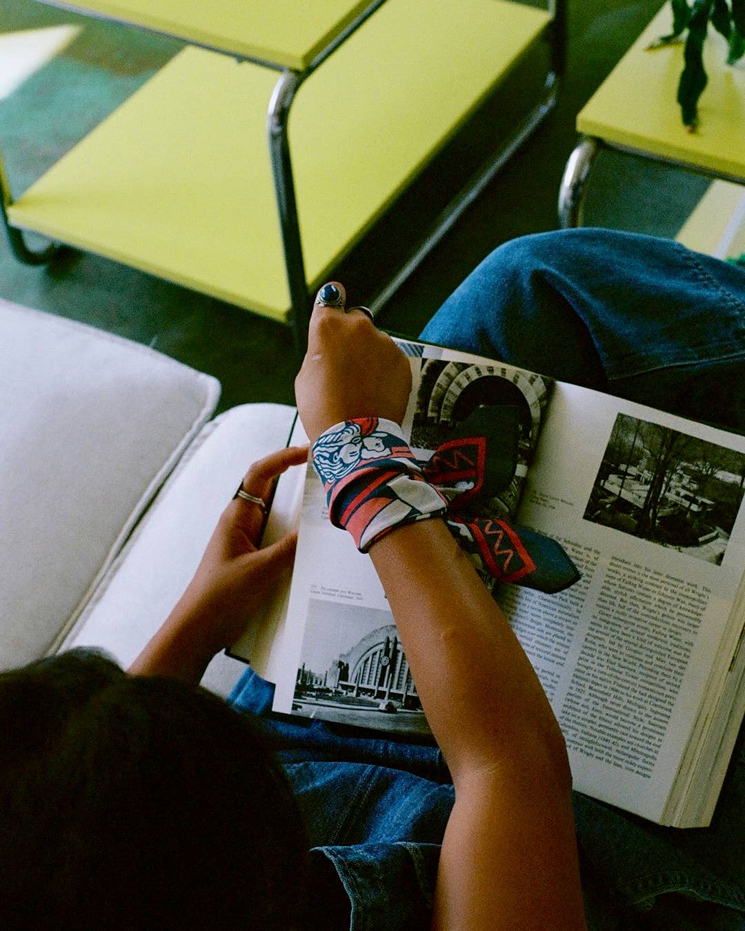 Person reading a book with colorful wrist bandana on a green chair