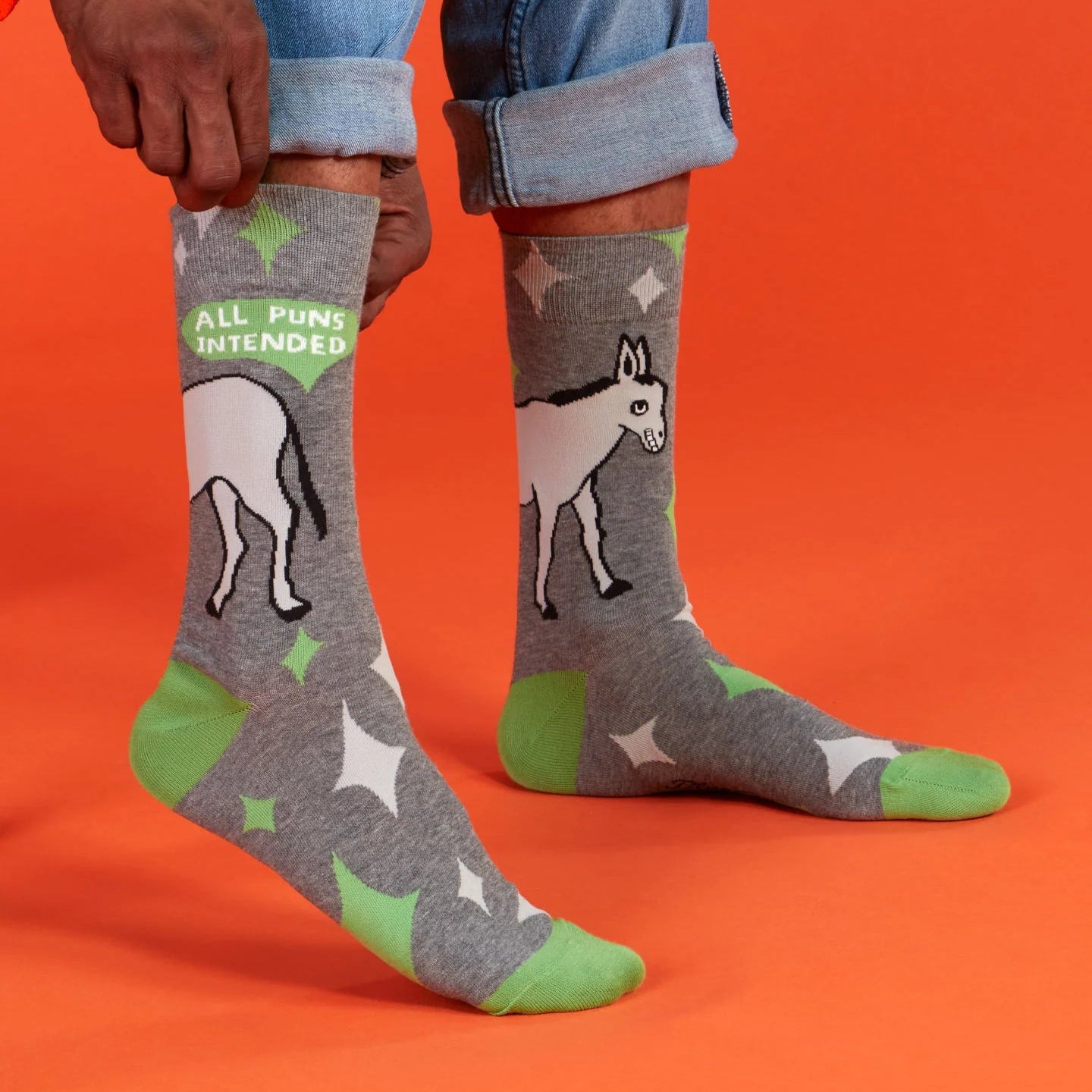 Person wearing gray socks with donkey design and 'All Puns Intended' text on an orange background