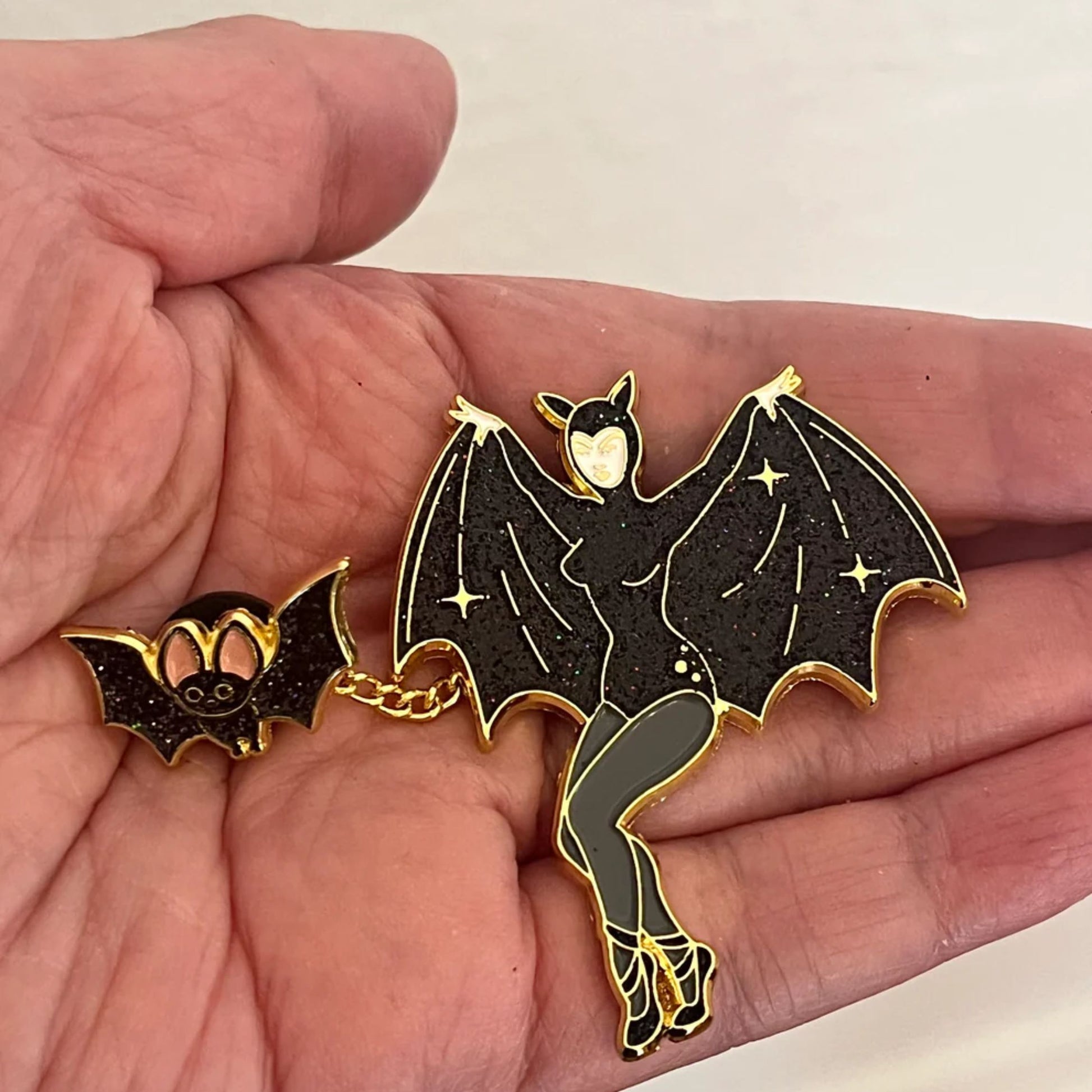Bat-shaped decorative enamel pin held in a hand 