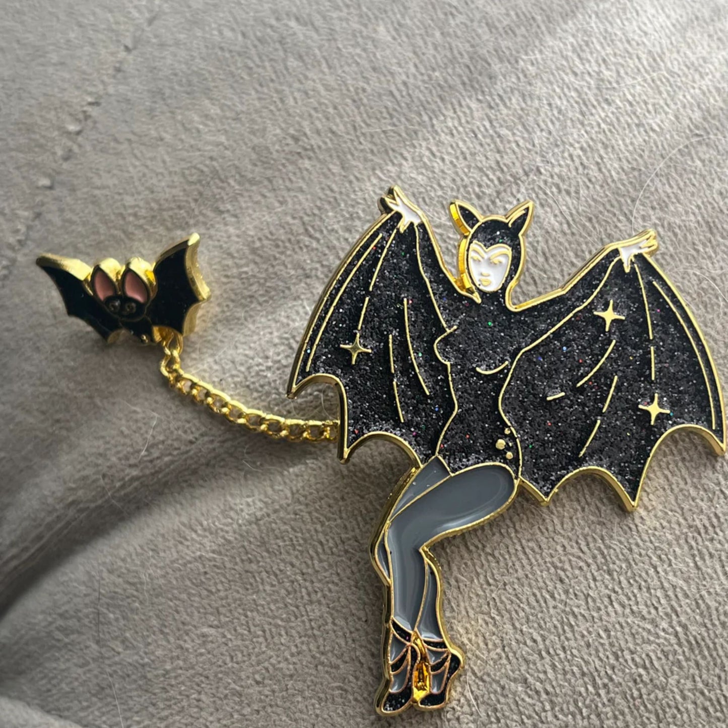 Bat-shaped brooch with a chain on a textured surface