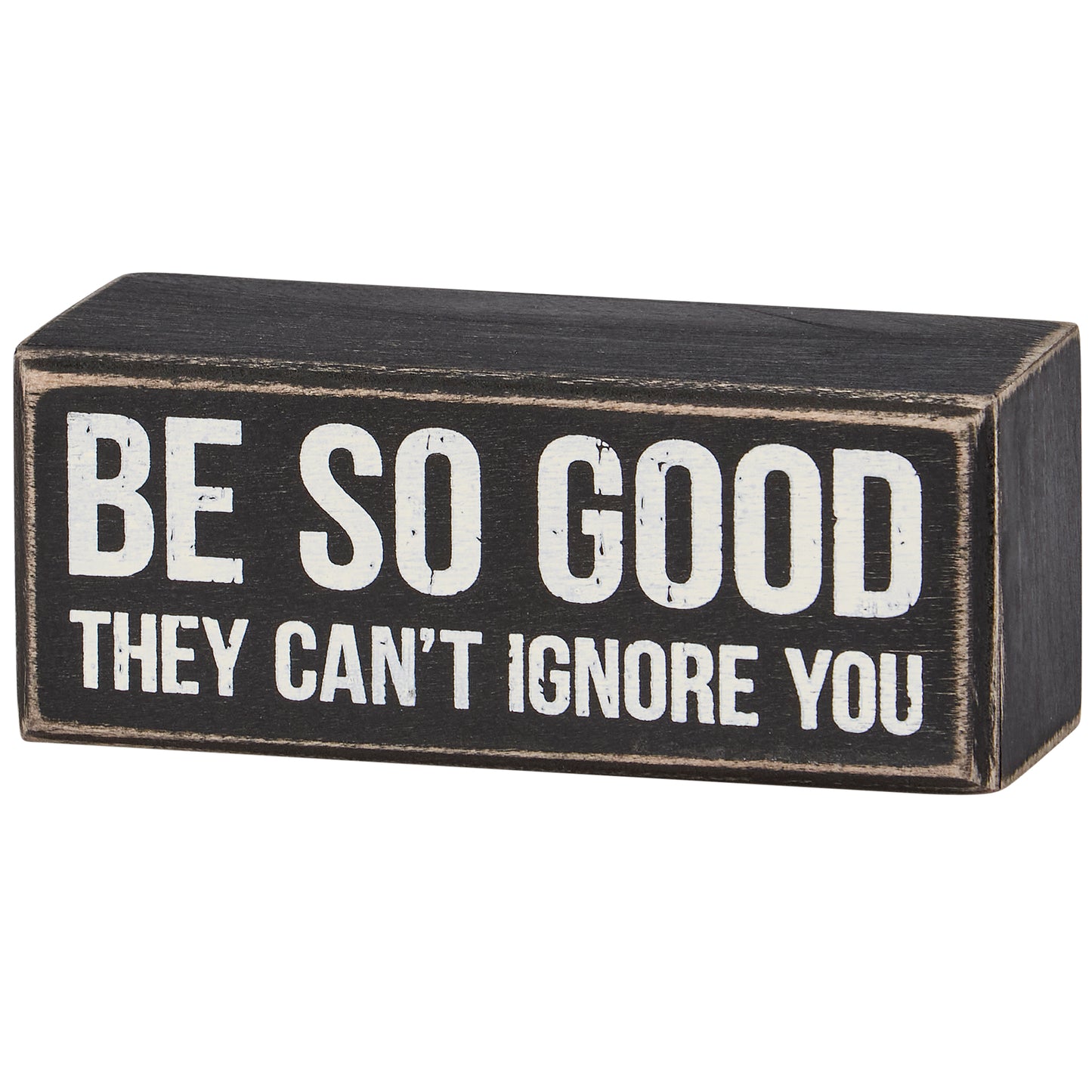 Black wooden block with white text 'BE SO GOOD THEY CAN'T IGNORE YOU' on a white background