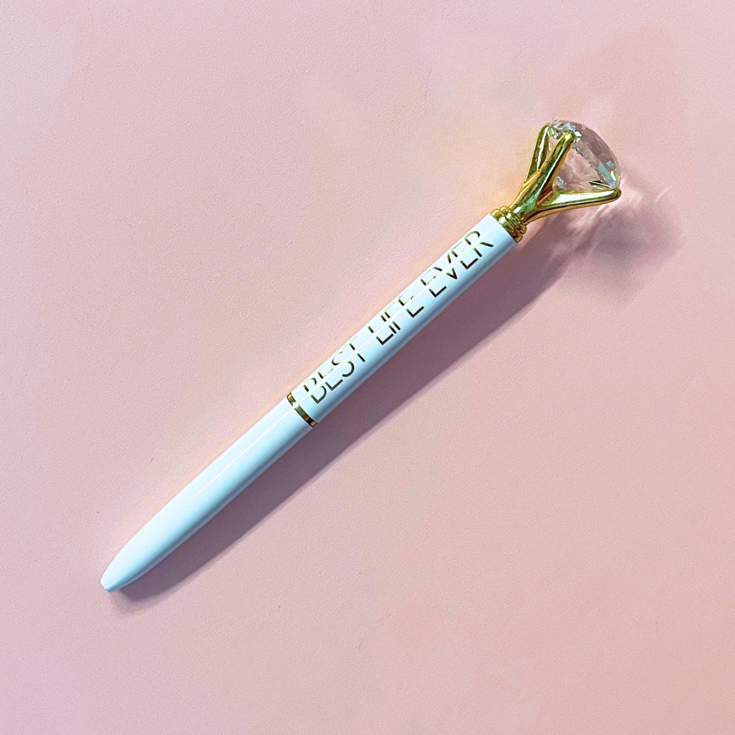 Pen with a gold tip labeled 'Best Life Ever' on a pink background