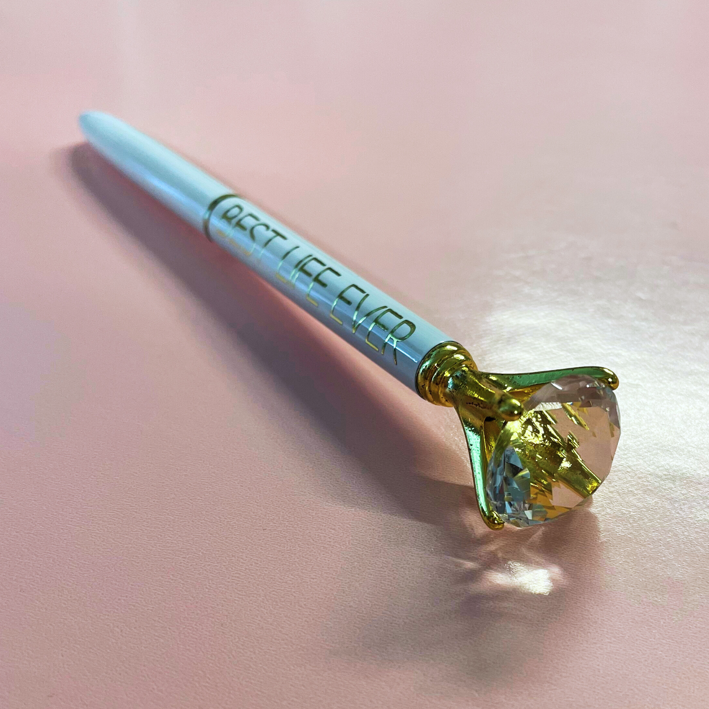Pen with a large gemstone on a light pink background