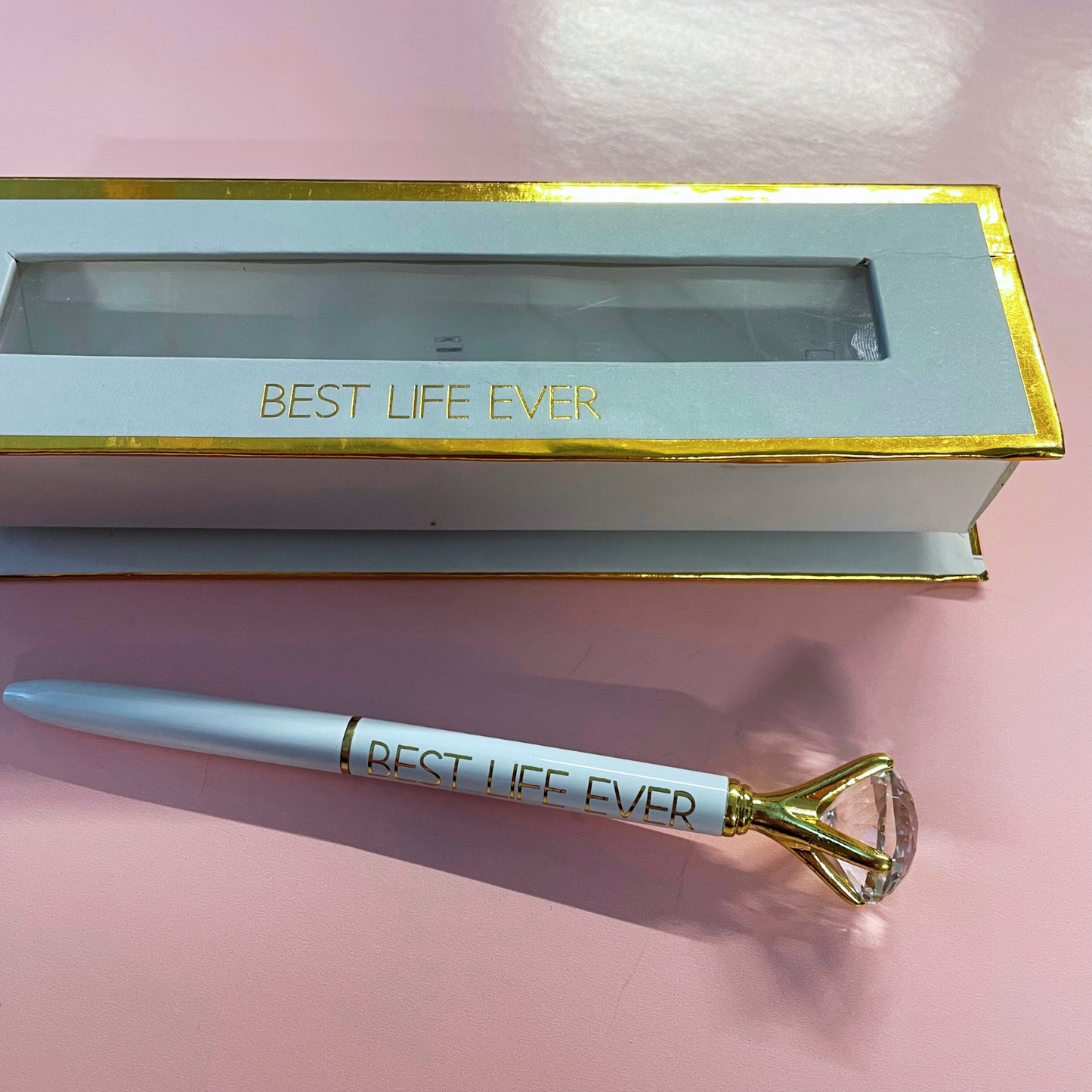 Pen and box with 'Best Life Ever' text on a pink background