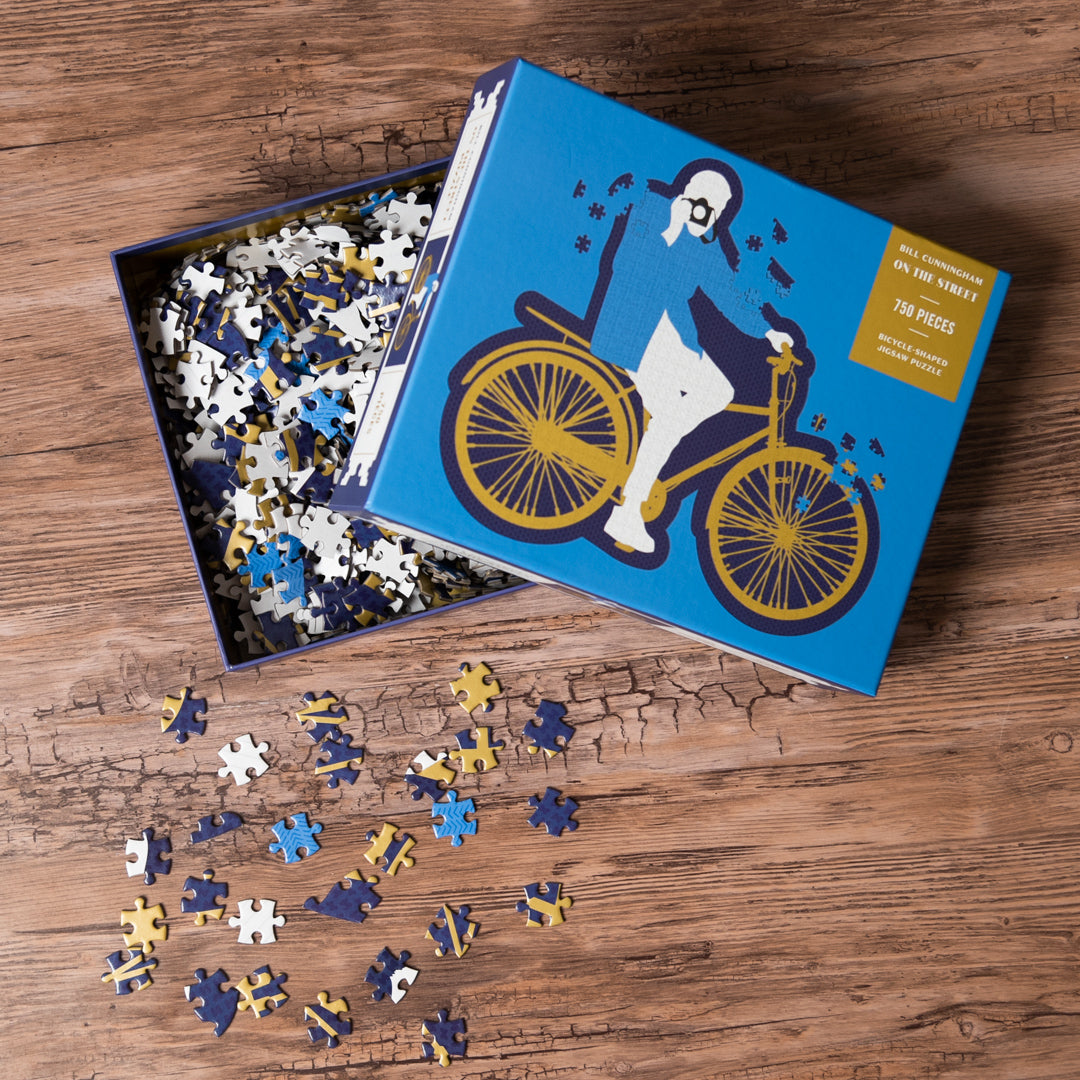 Jigsaw puzzle with a dog on a bicycle design, partially completed, on a wooden surface.