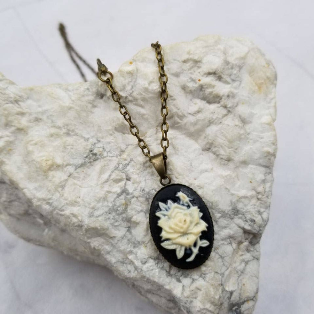Necklace with a black pendant featuring a white floral design on a textured stone surface.