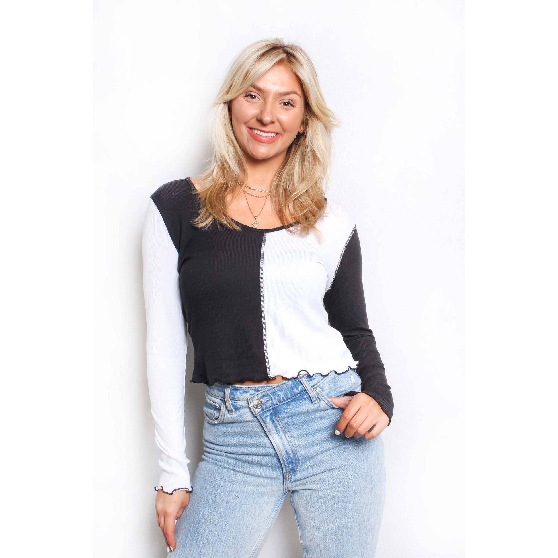 Woman wearing a black and white top with blue jeans on a white background