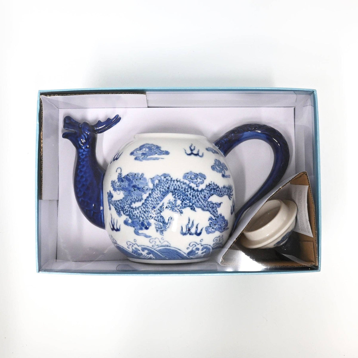 Blue and white ceramic teapot with dragon design in a box on a white background