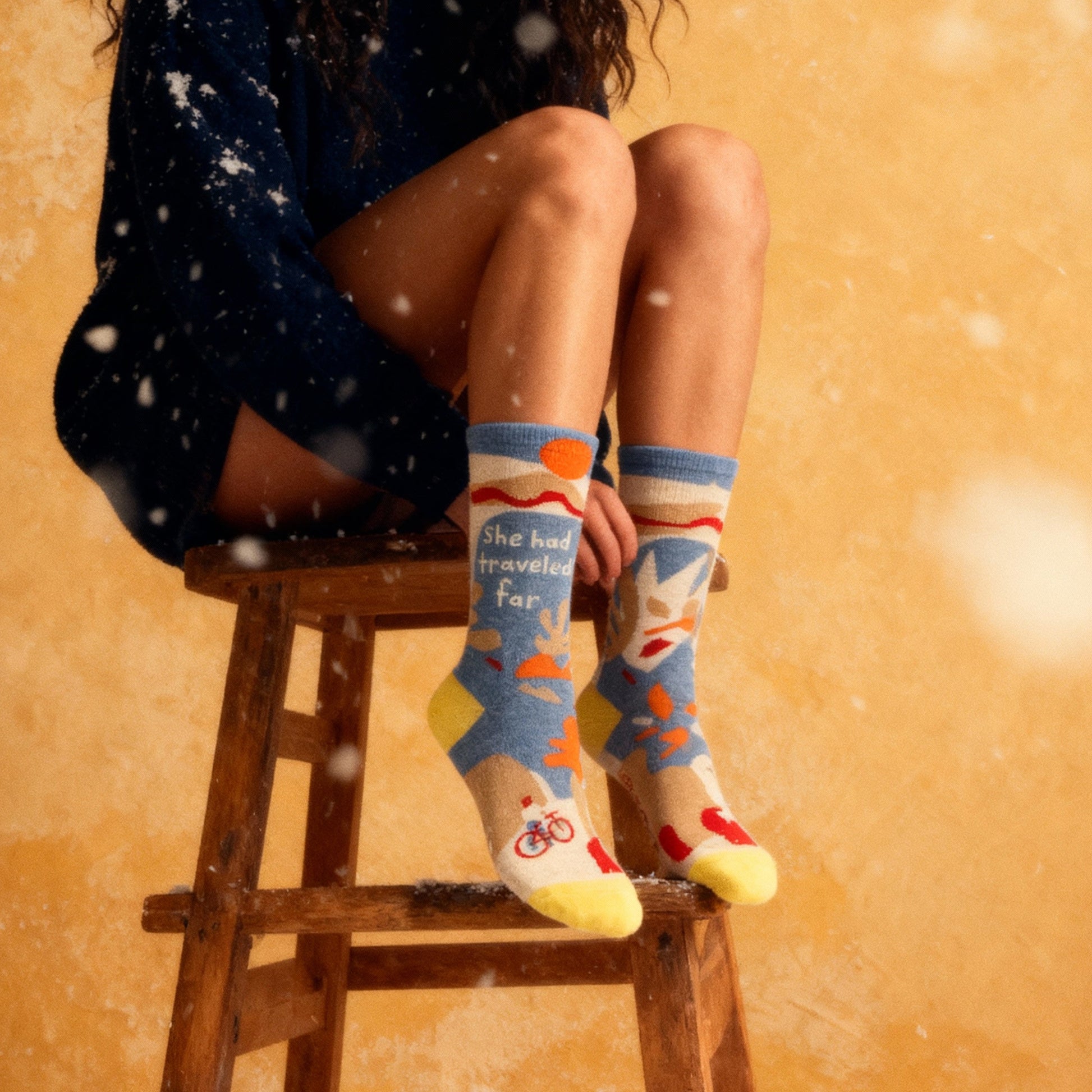 Woman sitting on a stool wearing colorful socks with a snowy background