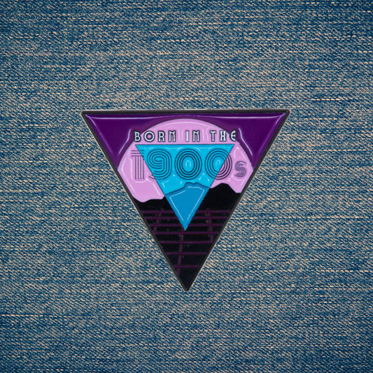 Triangular enamel pin with 'Born in the 1900s' design on a denim background