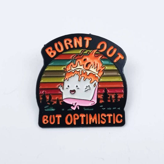 Enamel pin with cartoon character and 'Burnt Out But Optimistic' text