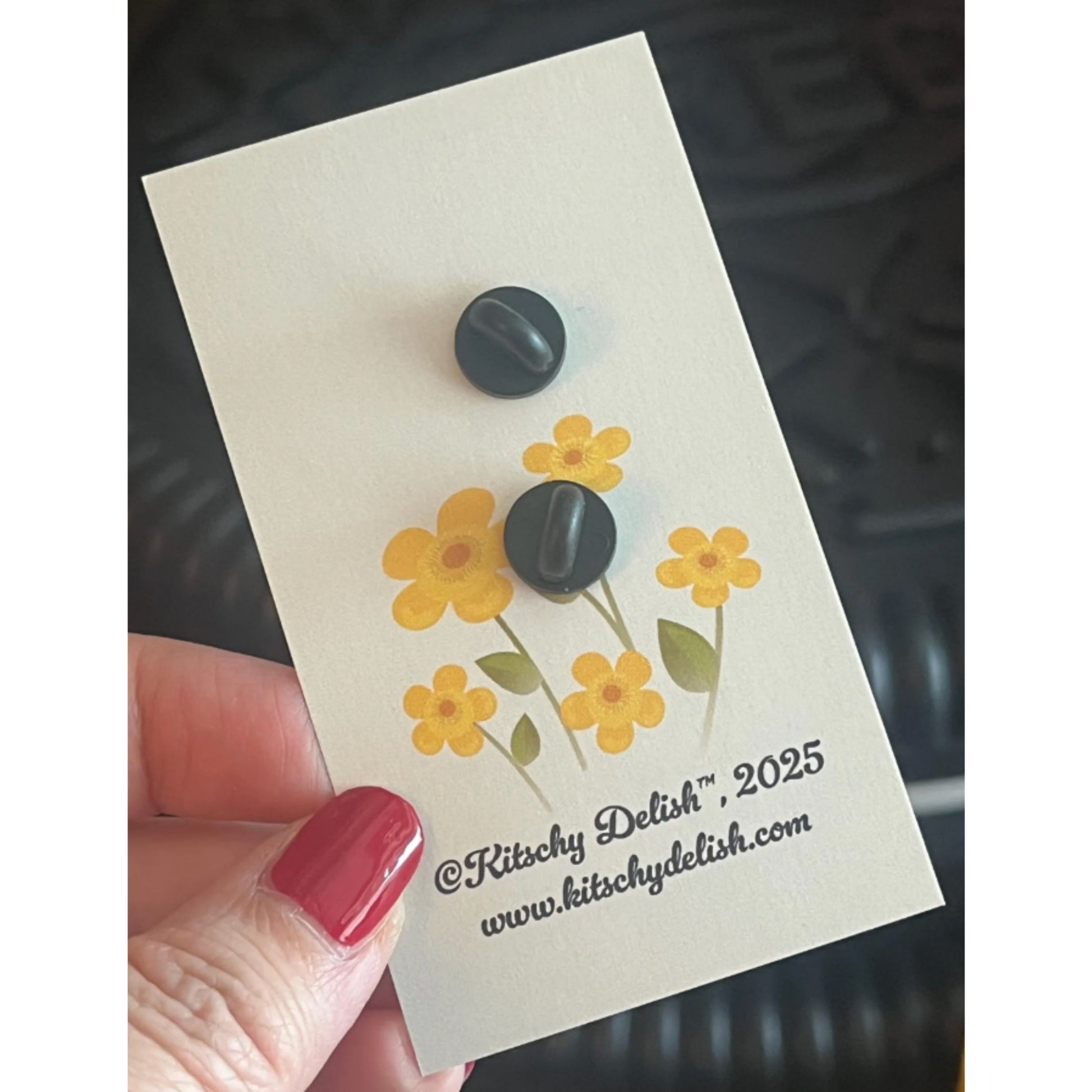 Back part of an enamel pin on a card with yellow flowers design