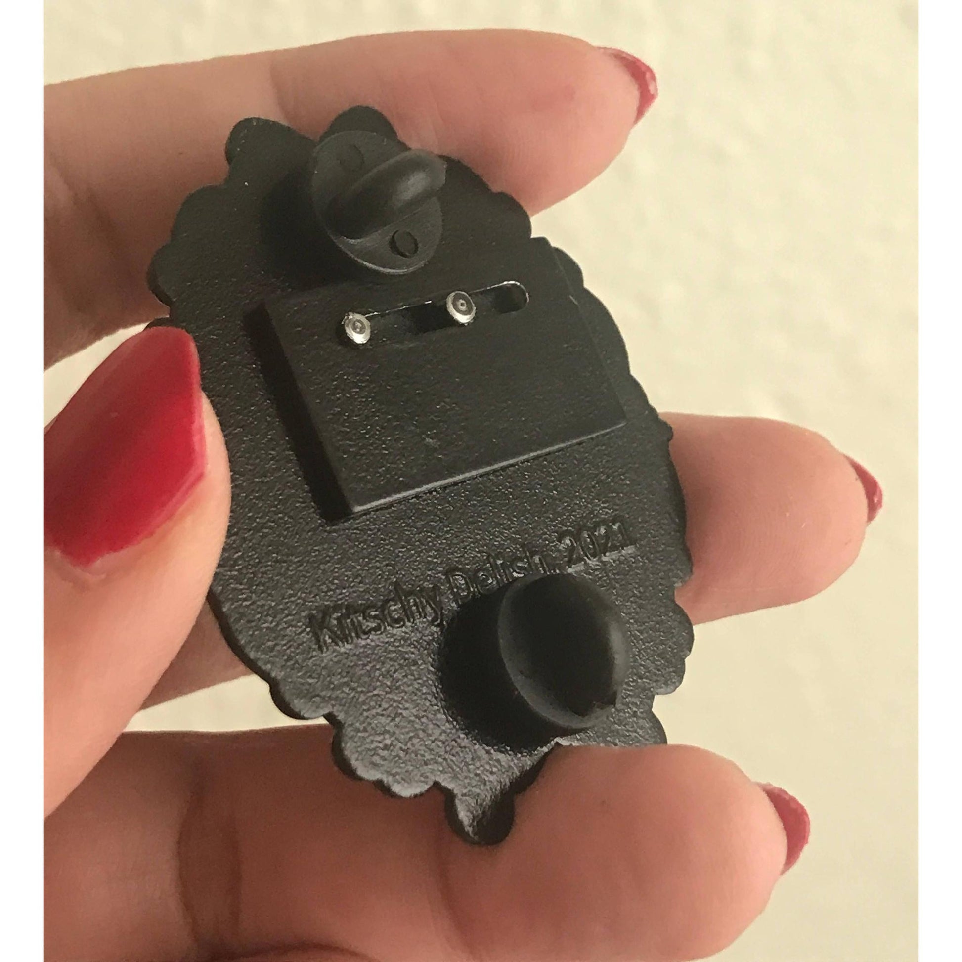 Back part of a sliding black enamel pin