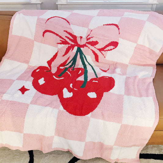 Pink and white checkered throw blanket with red cherries and a pink bow design.