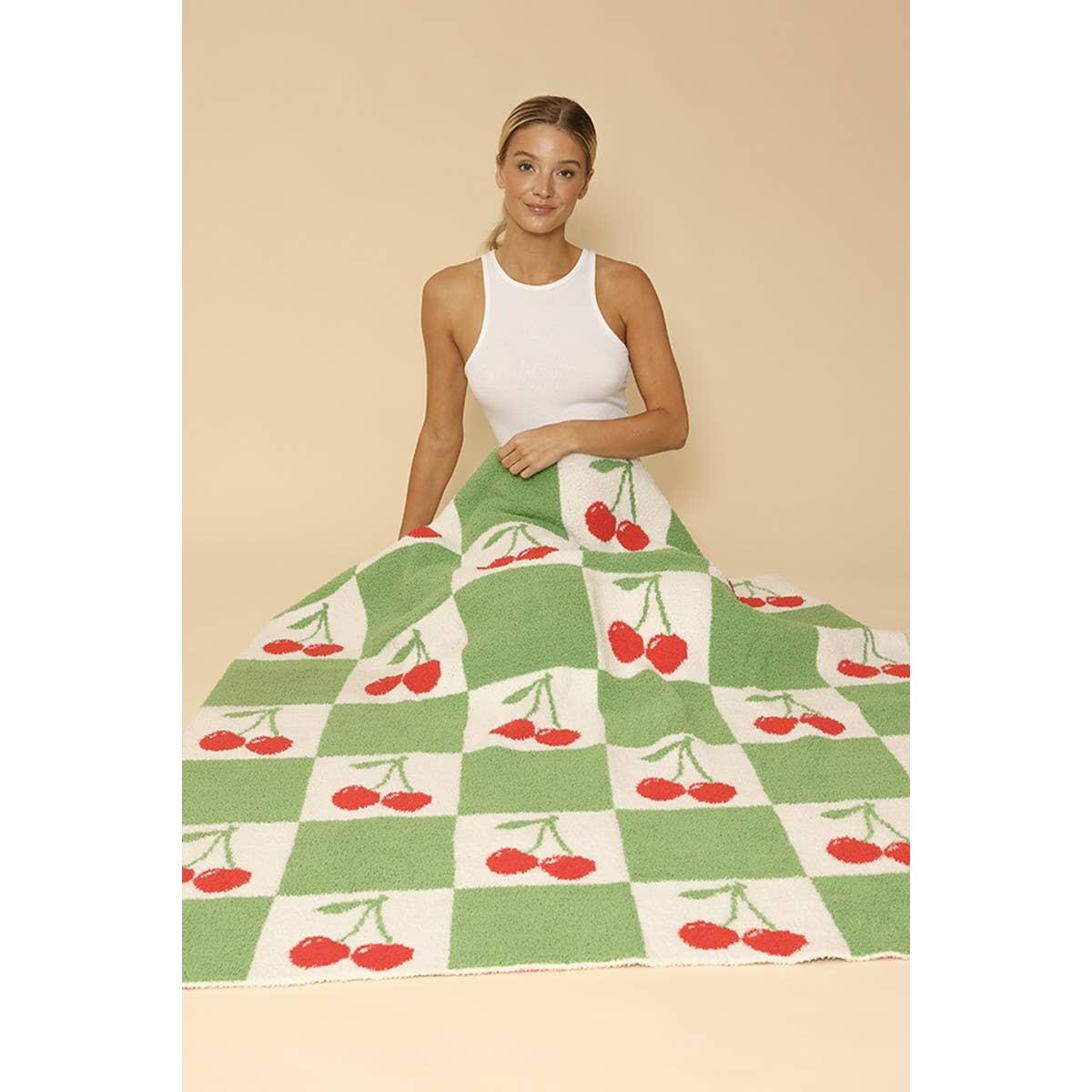 Woman holding a green and white checkered blanket with red cherries on a beige background