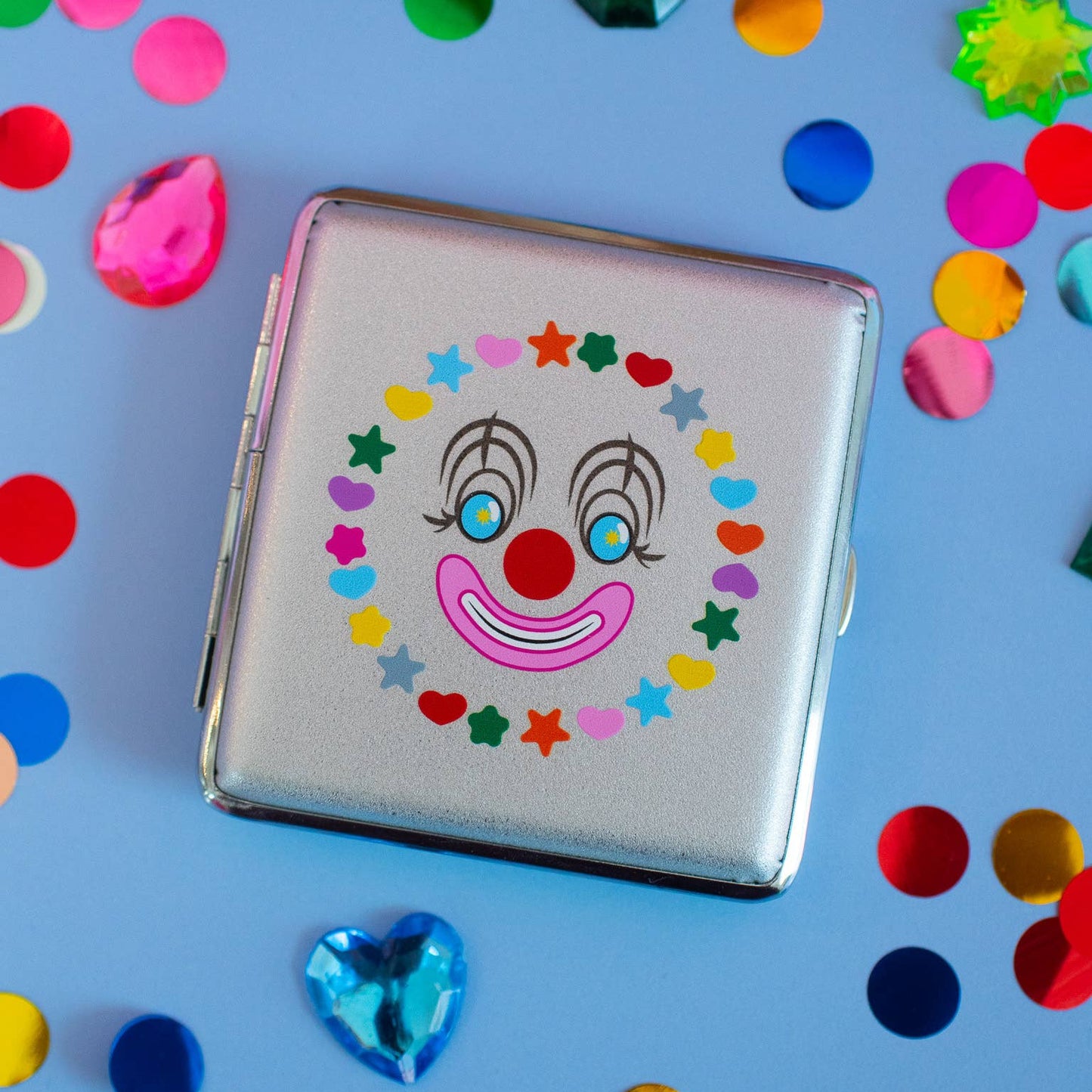 Cigarette case with clown face design on a blue background with colorful confetti