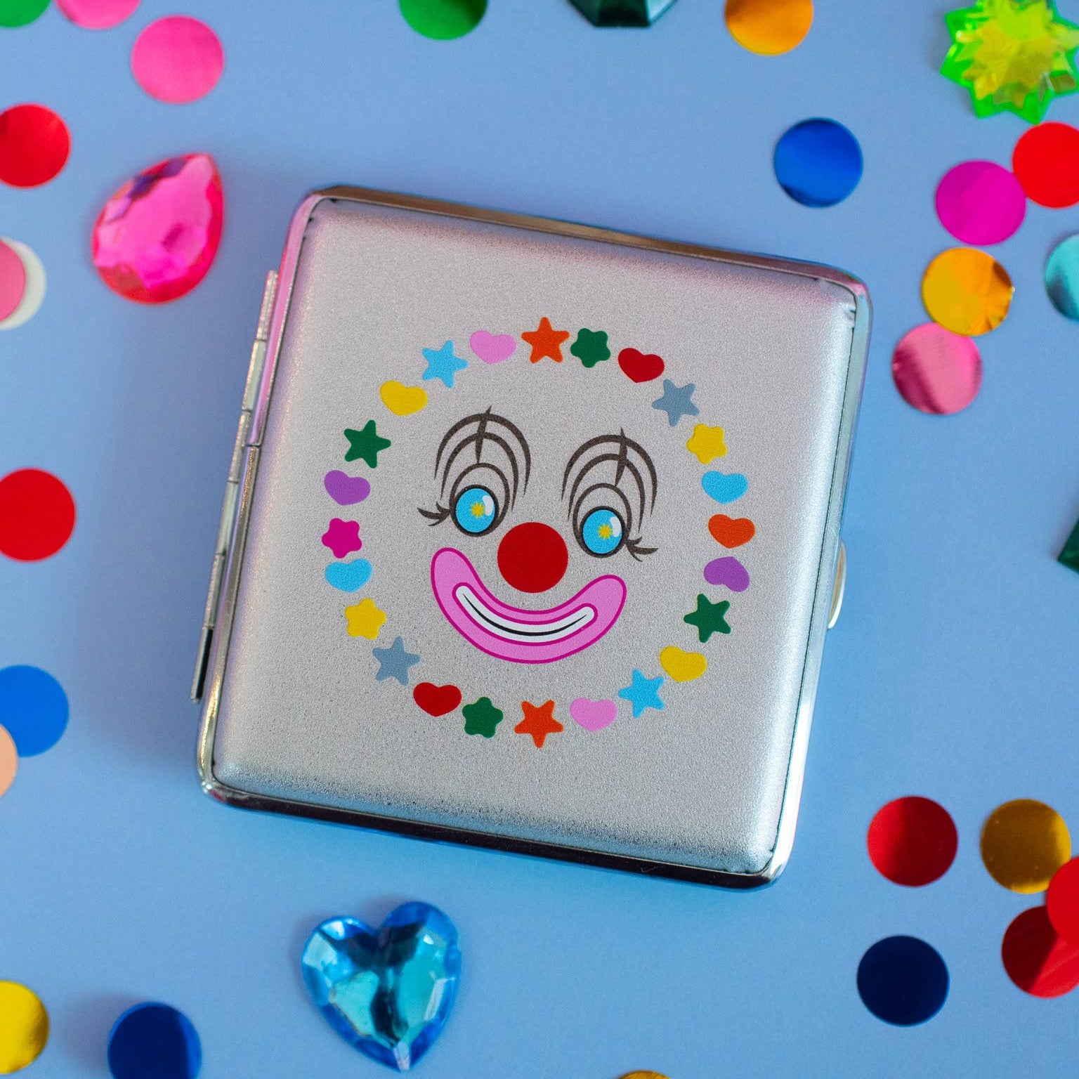 Cigarette case with clown face design on a blue background with colorful confetti
