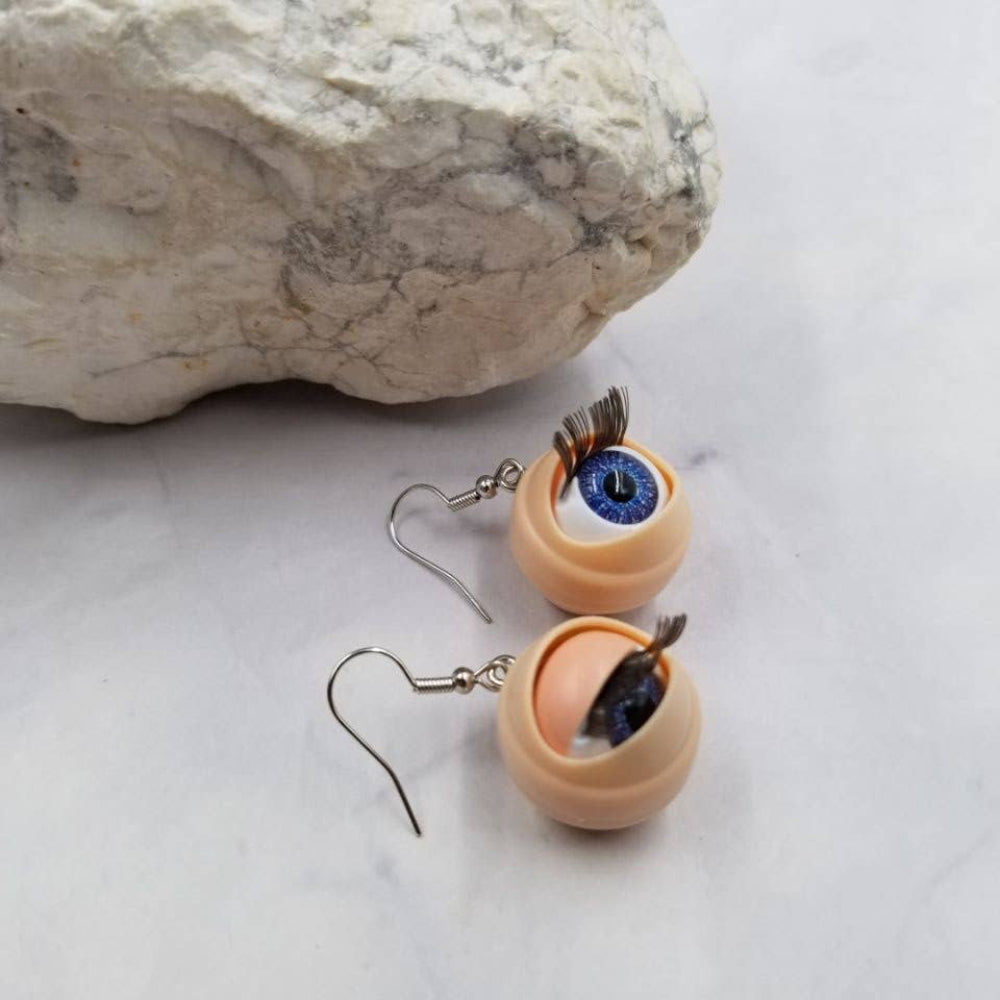 Earrings with eye design on a stone surface