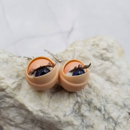 Eyeball-shaped earrings on a marble surface