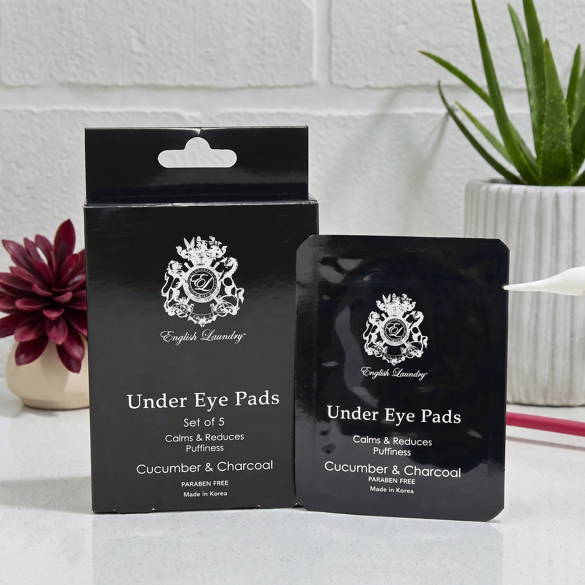 Black packaging of English Laundry Under Eye Pads with a white logo on a light gray surface.