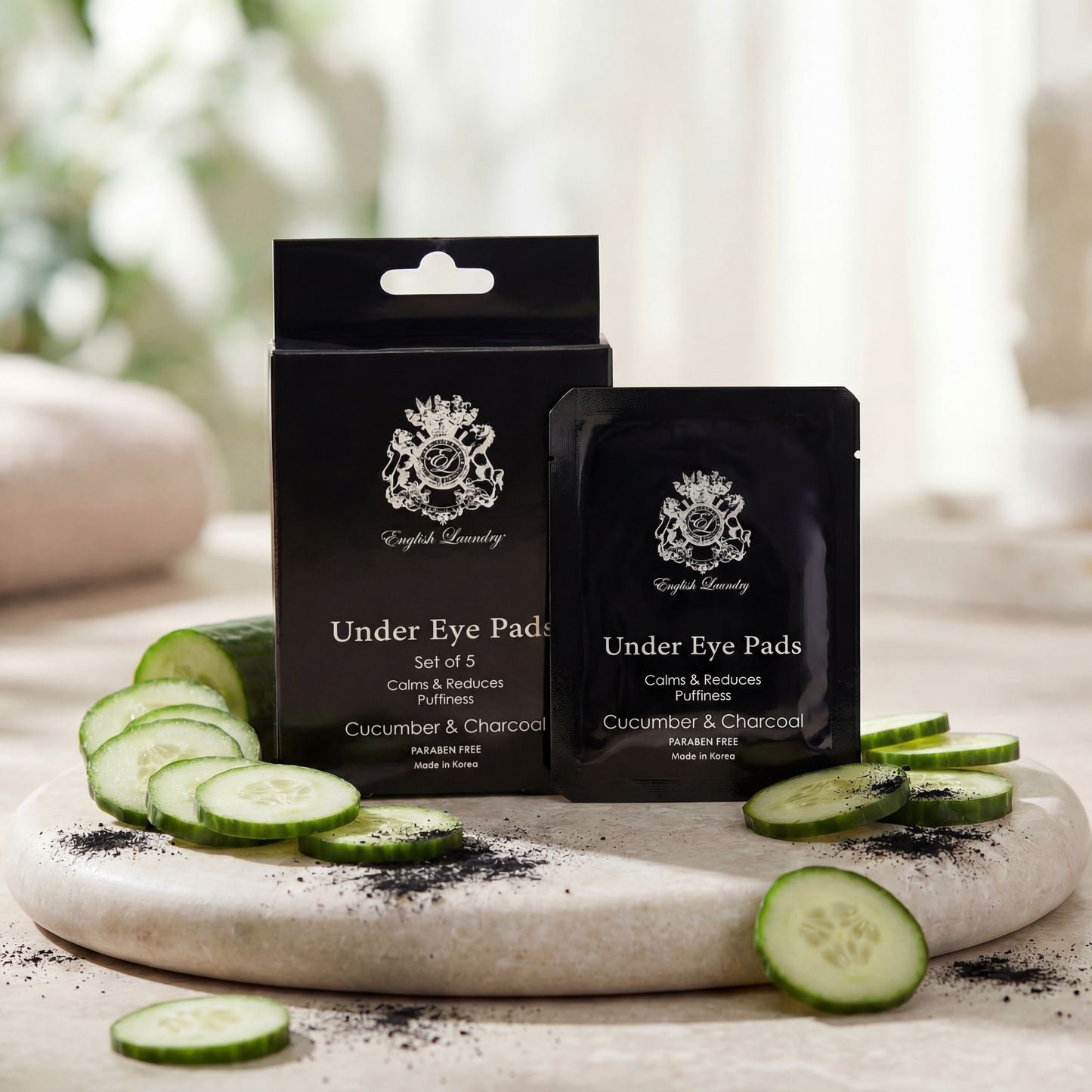 Under eye pads packaging with cucumbers and charcoal on a marble surface