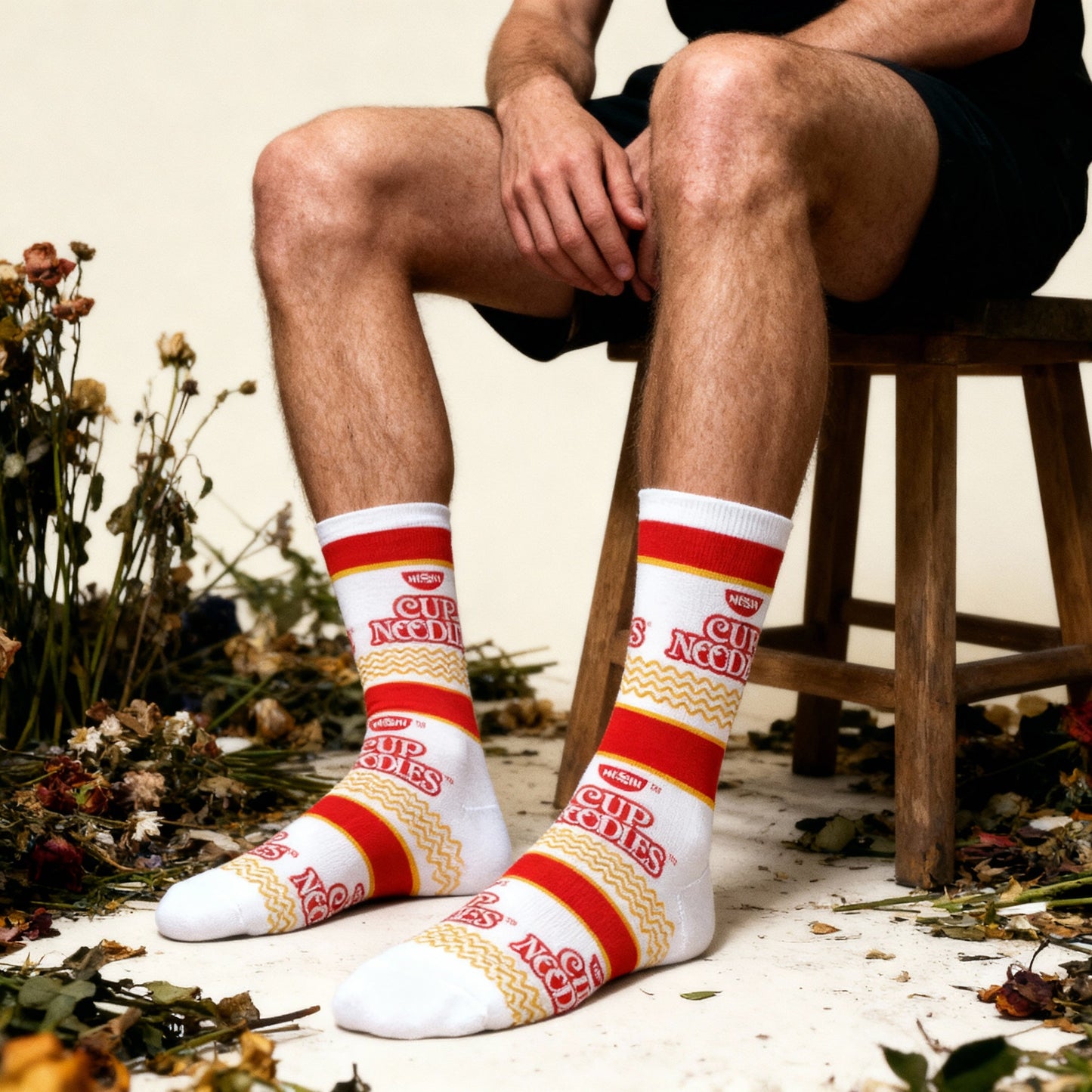 Person wearing socks with branding sitting on a stool surrounded by flowers.