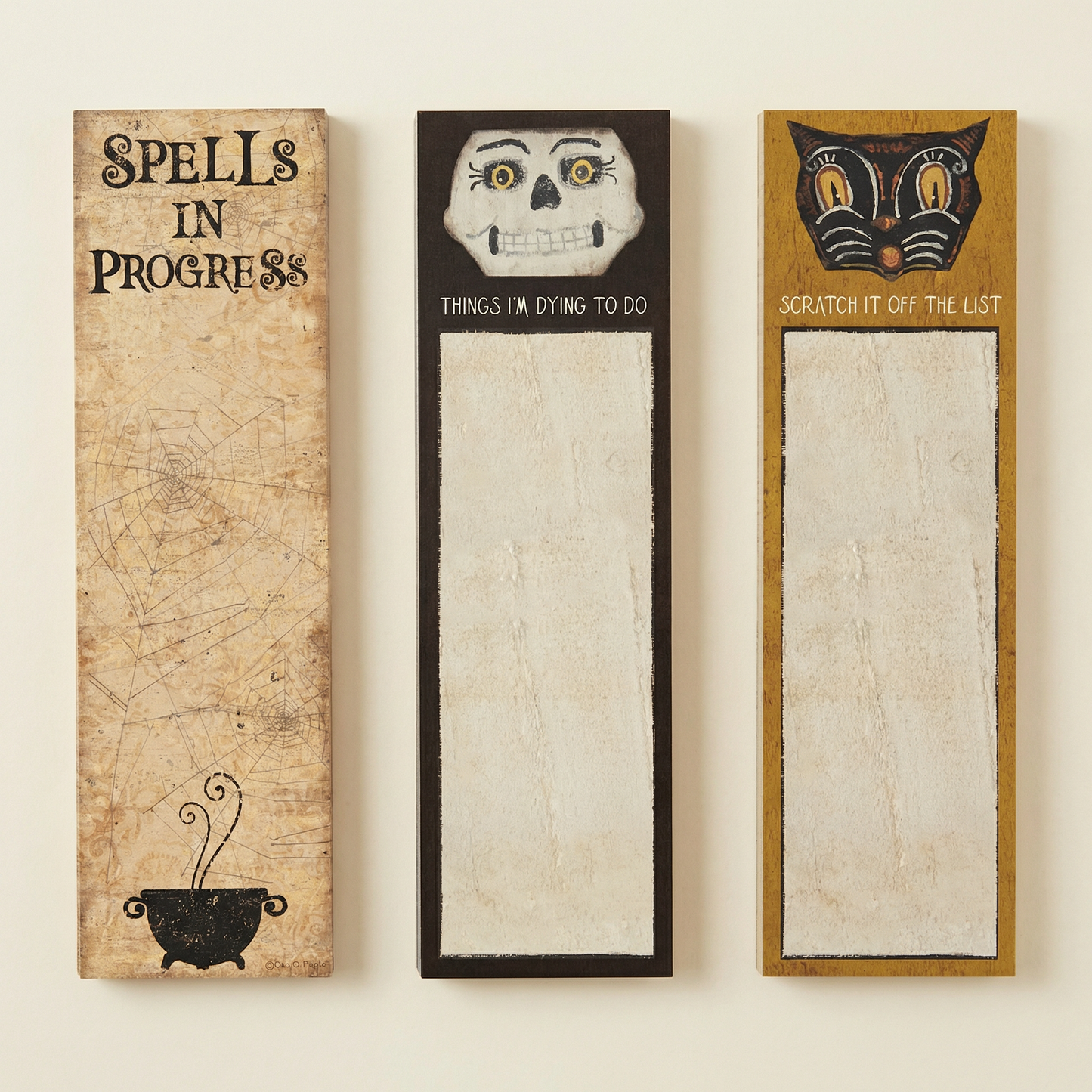 Three Halloween-themed notepads with decorative designs on a beige background
