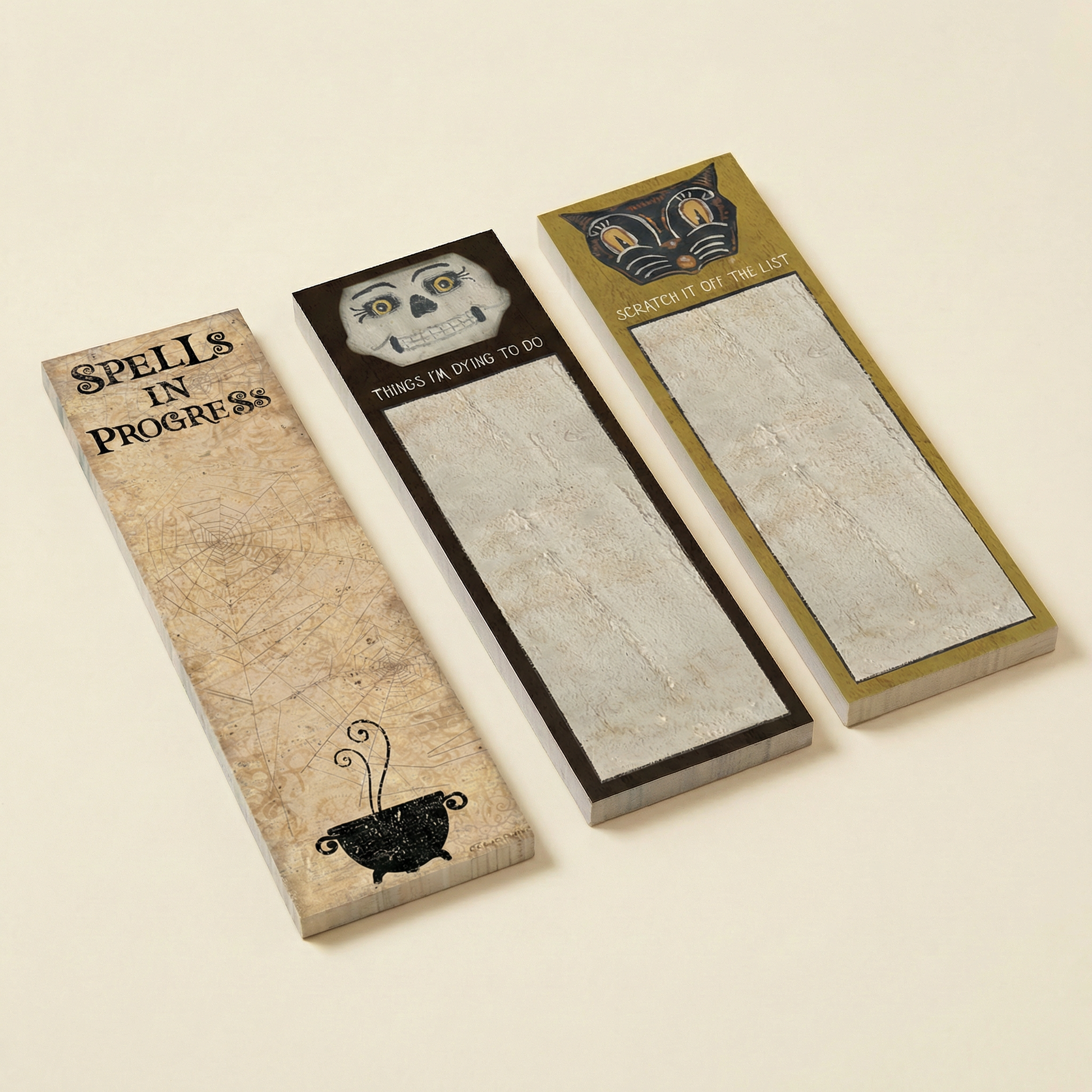 Three decorative notepads with unique spooky designs on a beige background