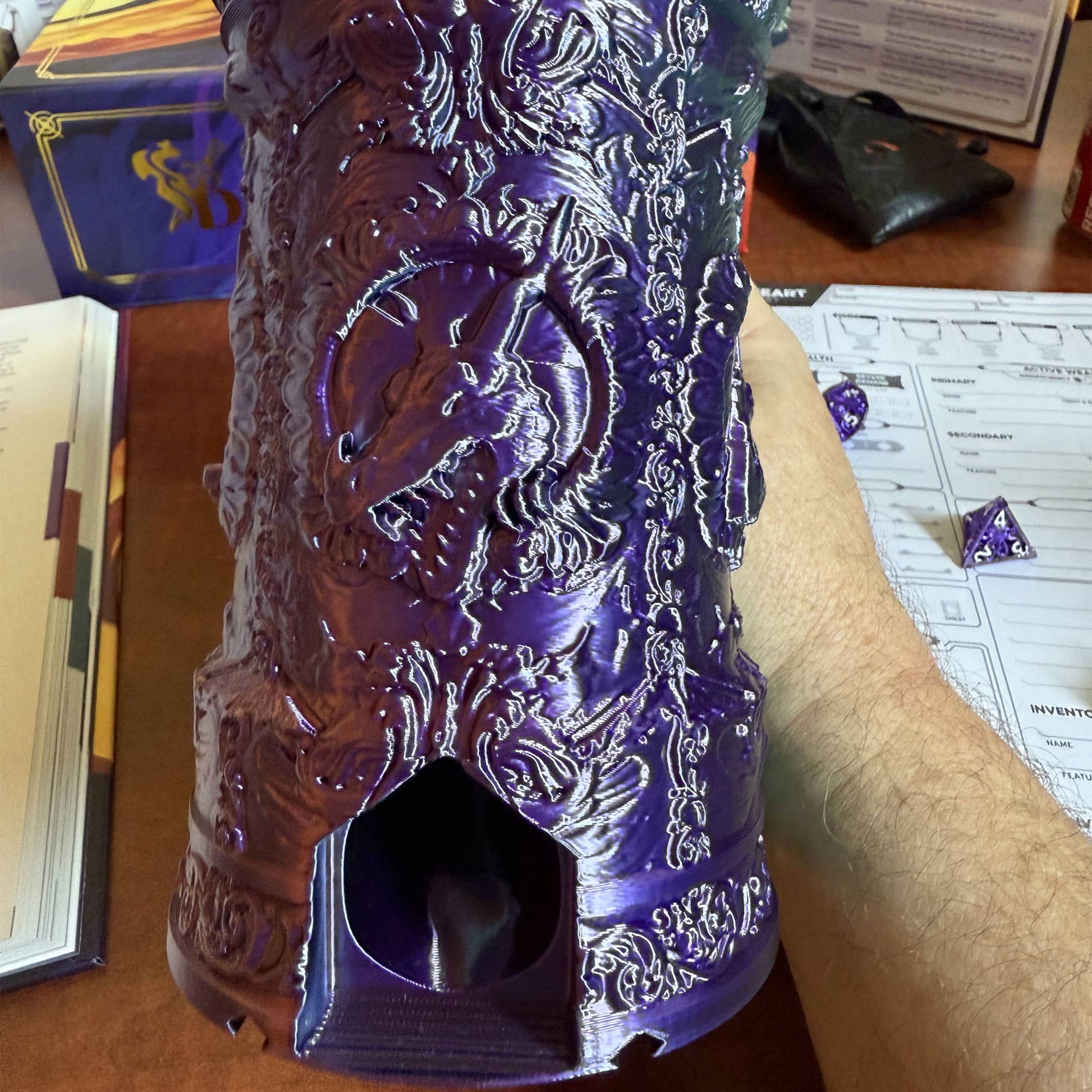 Decorative purple object with intricate designs held by a person on a table.